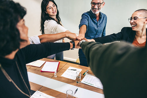 Ecstatic businesspeople bringing their fists together in a boardroom
