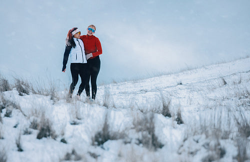 Women pause from running on a mountain hillside in winter snow