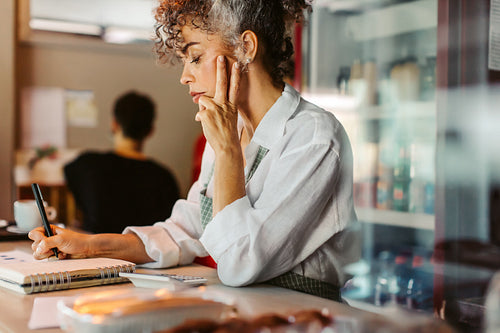 Focused entrepreneur doing her budget in her coffee shop