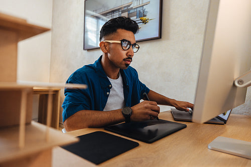 Young professional working on architectural design using a digital drawing tablet