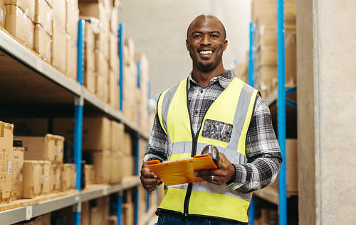 Happy young warehouse worker smiling at the camera