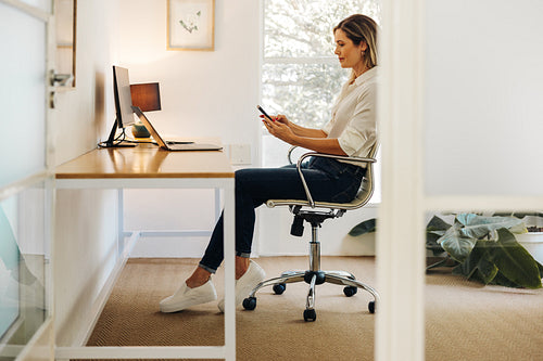 Cheerful businesswoman using a smartphone in her office