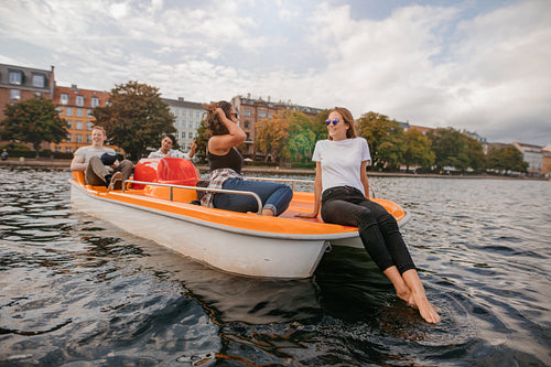 Teenage friends relaxing on pedal boat in lake