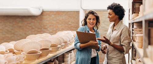Happy young businesswomen having a discussion in their ceramic store
