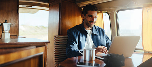 Focused planning: Man works on his laptop during a coastal stop