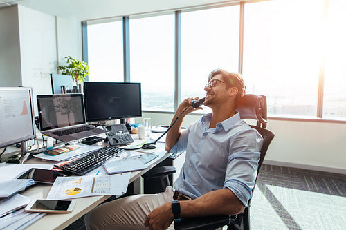 Business investor in a happy mood talking over phone in office.
