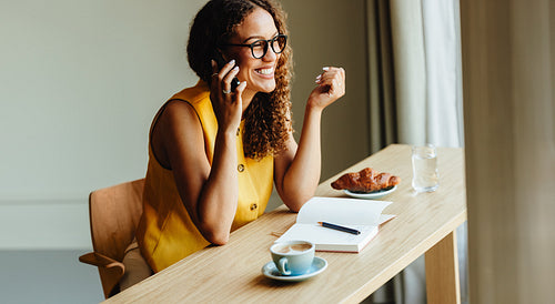 Woman on a phone call at a table with coffee indoors