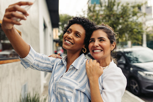 Cheerful young women taking a selfie together outdoors