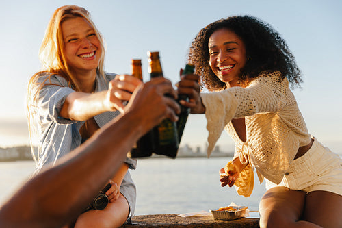 Friends toasting drinks at sunset by the waterfront