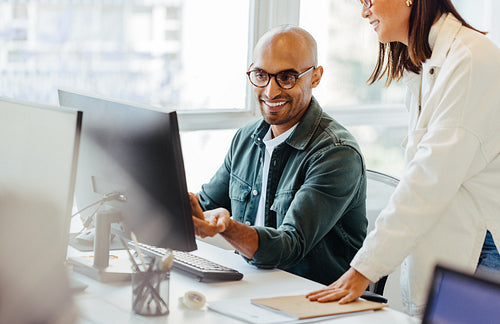 Software engineers using a computer and having a discussion in an office