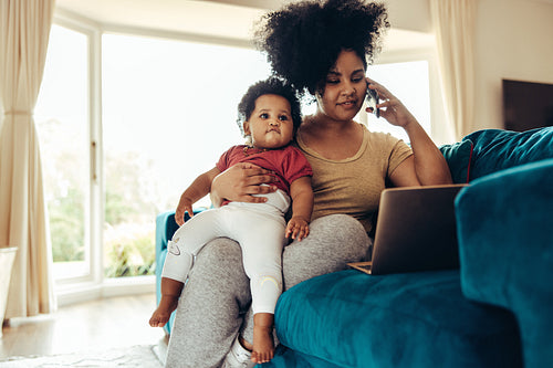 Mother holding baby while working at home