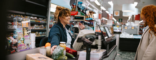 Cashier assisting customer at supermarket checkout