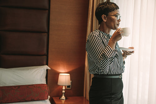 Businesswoman standing in hotel room drinking coffee