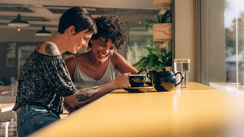 Female friends at cafe using mobile phone