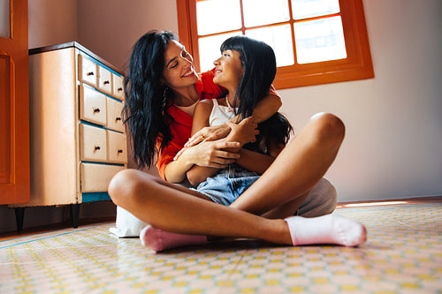 Happy mother and daughter embracing on a colorful tiled kitchen floor