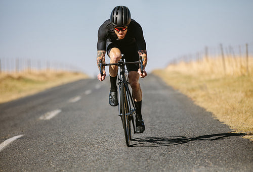 Sportsman cycling outside on country road