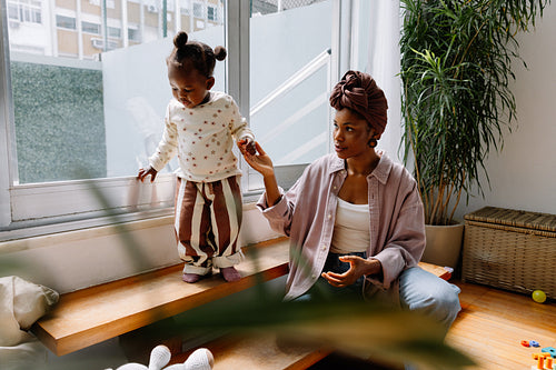 Mother assisting child near window