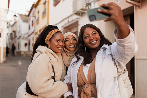 Three multicultural friends taking a selfie together outdoors