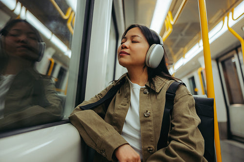 Commuter on train listening with headphones, eyes closed