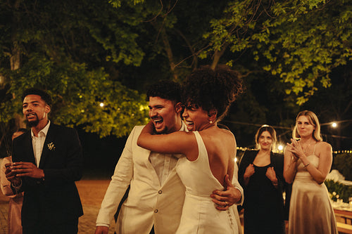 Bride and groom celebrating with friends at beautiful outdoor evening wedding