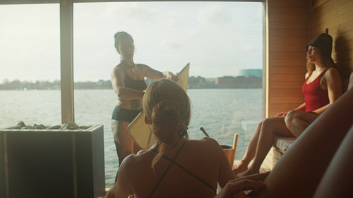 Sauna ritual with women relaxing during aufguss spa session by the water