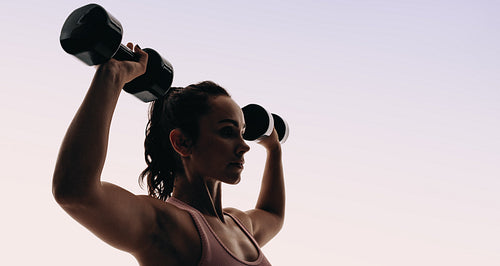 Focused female athlete engages in intense upper body training at studio gym