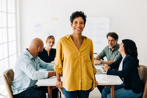Black business woman standing in a boardroom with her team in the background
