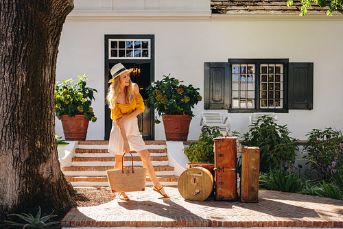 Happy female traveller leaving a hotel with her bags