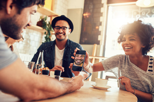 Friends in cafe and looking at the photos on smart phone