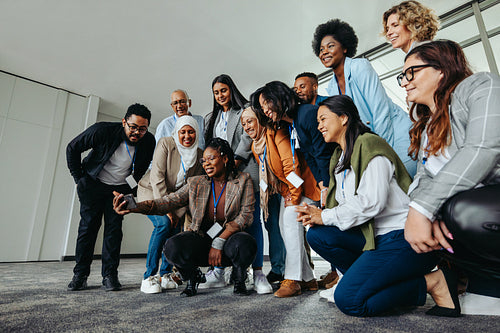 Multiethnic group of businesspeople smiling and taking a group photo at an office event
