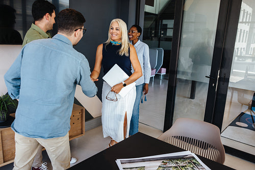 Colleagues greeting each other in a modern office setting during a meeting