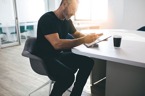 Mature businessman working on his digital tablet