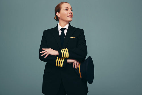 Cheerful airline pilot looking away thoughtfully