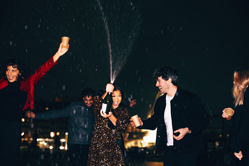 Friends celebrating together outdoors with champagne on a festive evening