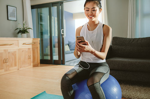 woman with smartphone relaxing on a fitness ball