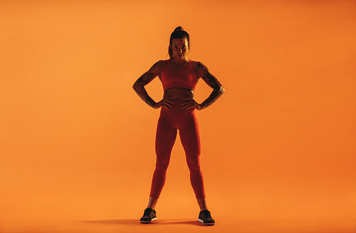 Fit woman standing against orange background