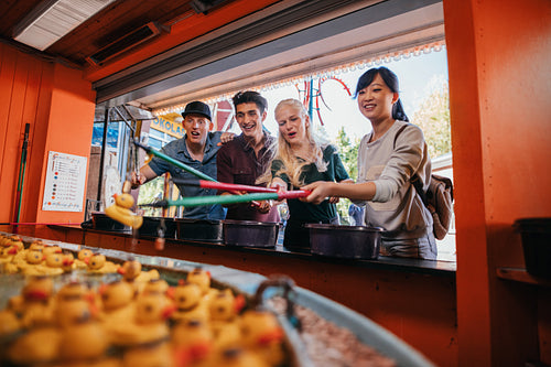 Group of friends playing fishing game at fairground
