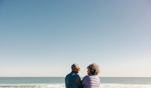 Happy elderly couple smiling at each other at the beach