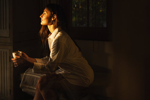 Woman having coffee in a dark hotel room