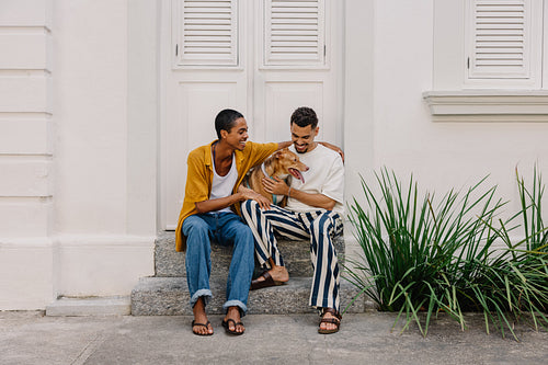 Young couple sitting with their dog on steps in a casual friendly moment