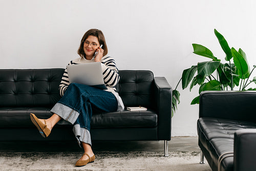 Woman managing smartphone communication while working from home in a relaxed setting