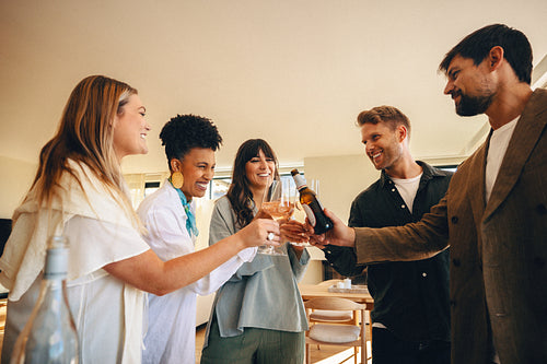 Friends celebrating together at a modern home with drinks and laughter