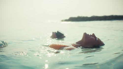 Relaxing woman enjoys a peaceful tropical ocean swim during a luxury beach vacation