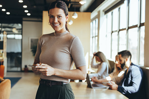 Cheerful businesswoman sending a text message on her phone