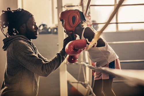 Boxing kid standing inside a boxing ring talking to his coach