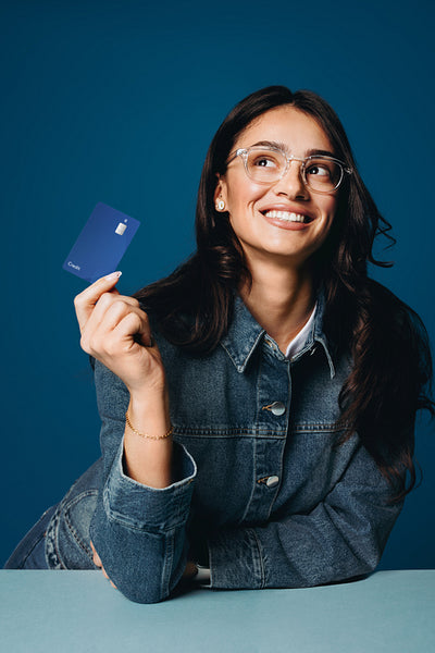 Smiling woman holds a credit card in the studio for purchase and banking use