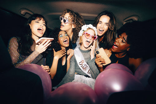 Excited friends and a bride-to-be in a car on the way to a bachelorette party