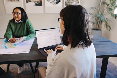 Businesswoman uses laptop during meeting to discuss trending projects and take notes