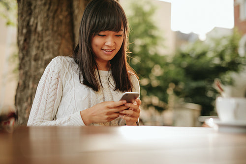 Woman using smart phone in a outdoor cafe.