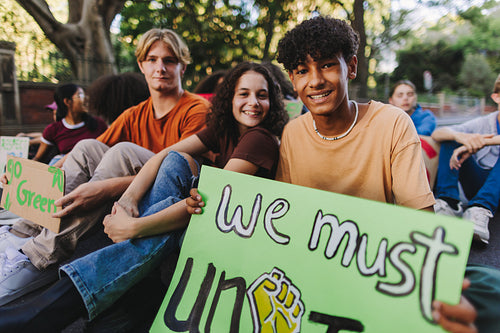 Diverse teenagers sitting at a climate change protest